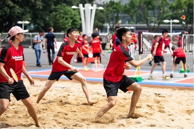 3 players playing AirBadminton outdoors on a sandy court