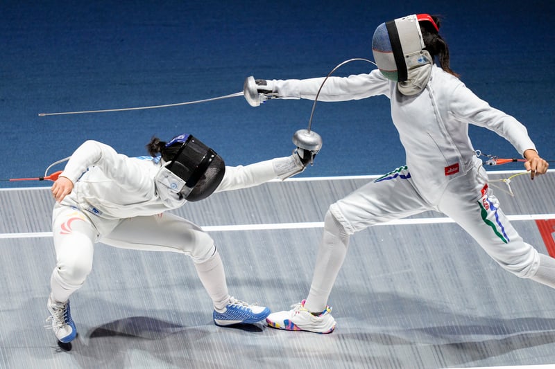Singapore’s Elle Koh (left) ducks under her Uzbek opponent’s sword and lands a blow to the face during the last 16 match in the women’s individual epee. (Photo: SNOC/ Kelly Wong)