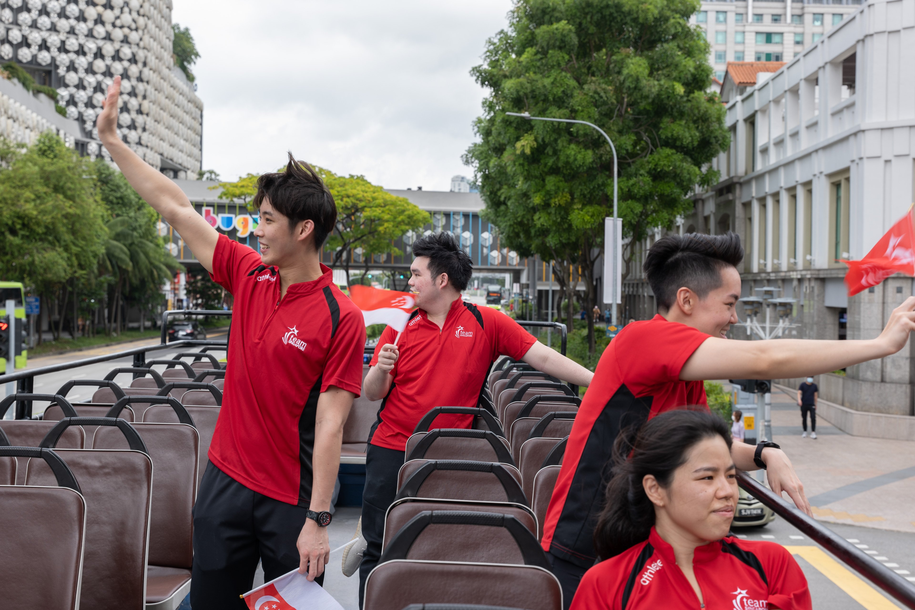 Athletes waving to crowd along bugis