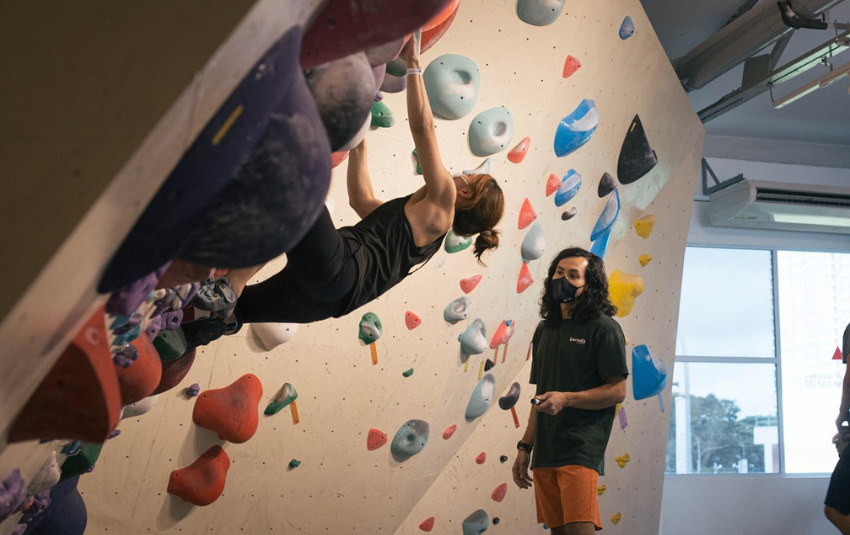 Woman trying bouldering with advice from an instructor at Boruda Climbing