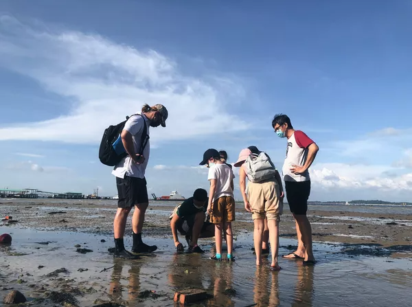 Asian family looking for seaside creatures in the sand