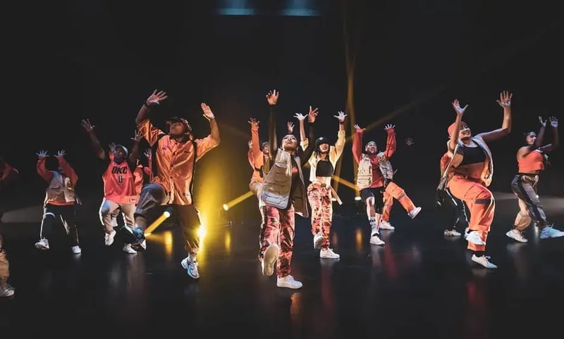 Dancers in orange outfits performing on stage