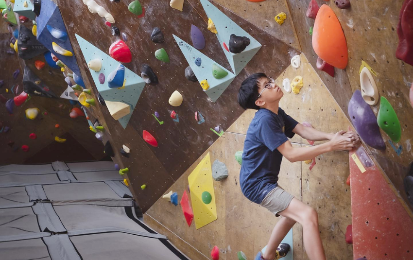 Young boy attempting bouldering at Kinetics Climbing