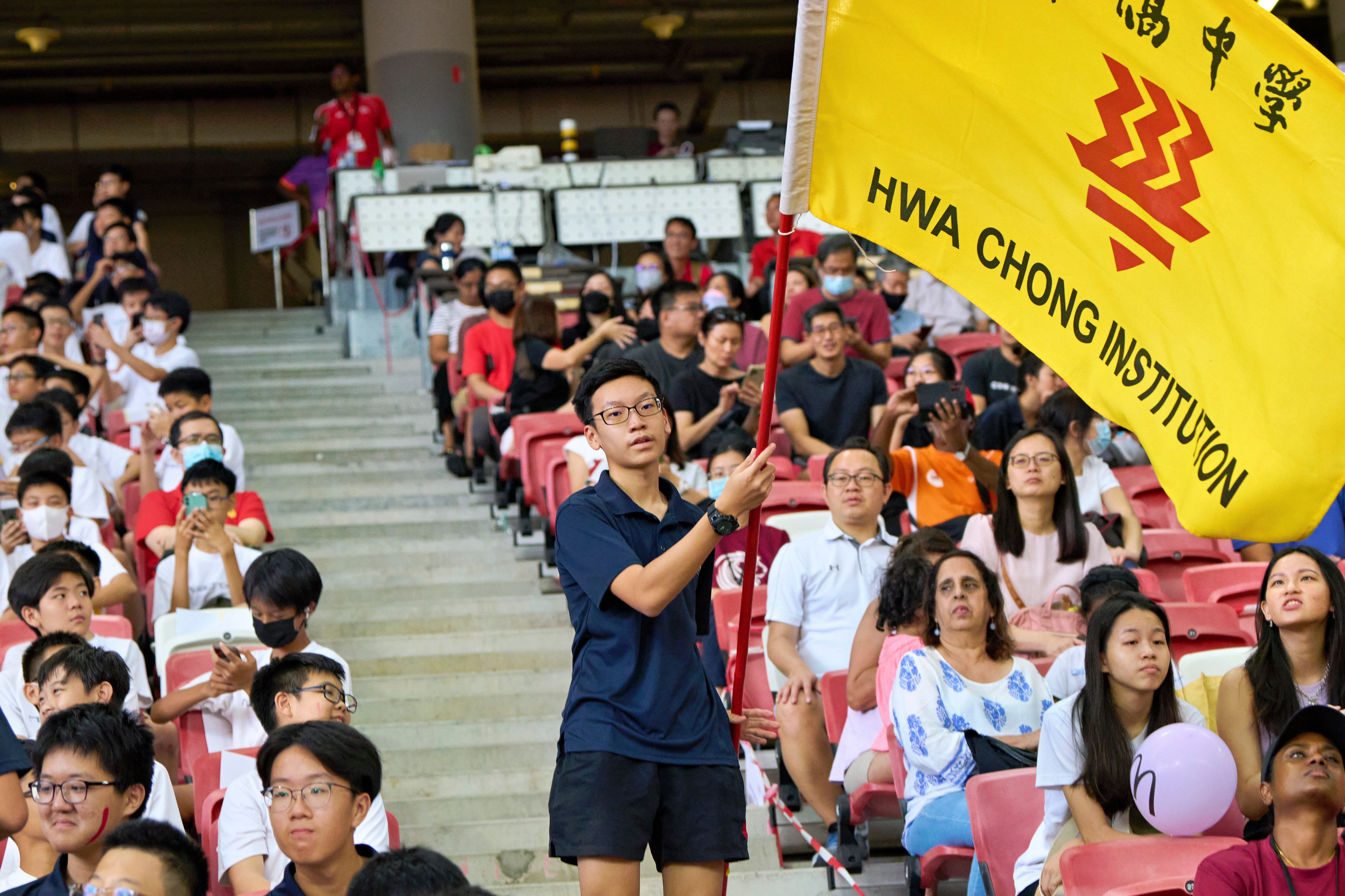 2023-04-28 NSG T&F Championships Photo by Eric Koh, Supporter from HCI waves the school flag with A Div Girls 100m win DSC05938
