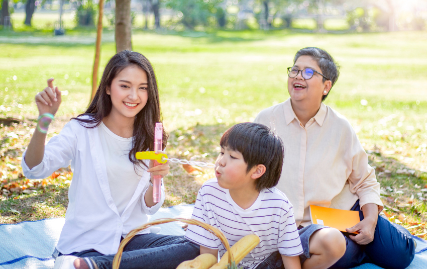 Young boy blowing bubbles while having a picnic with the family