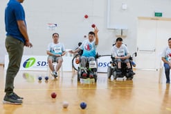 Photo of Boccia player on wheelchair tossing the boccia ball into play